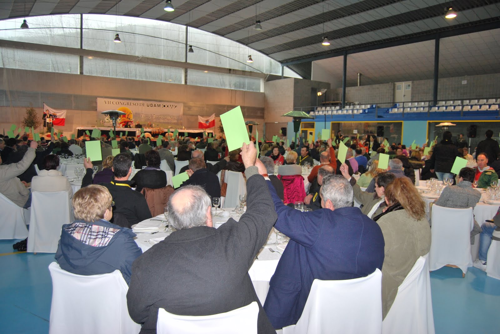 Votación en una asamblea de asociados levantando carteles verdes los que votaban a favor